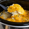 ['A close-up of cheesy potatoes in a slow cooker.']