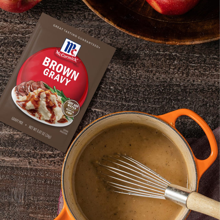 A package of McCormick Brown Gravy mix next to a pot of brown gravy with a whisk.