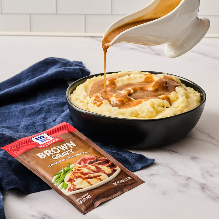A bowl of mashed potatoes with McCormick Brown Gravy being poured over it.