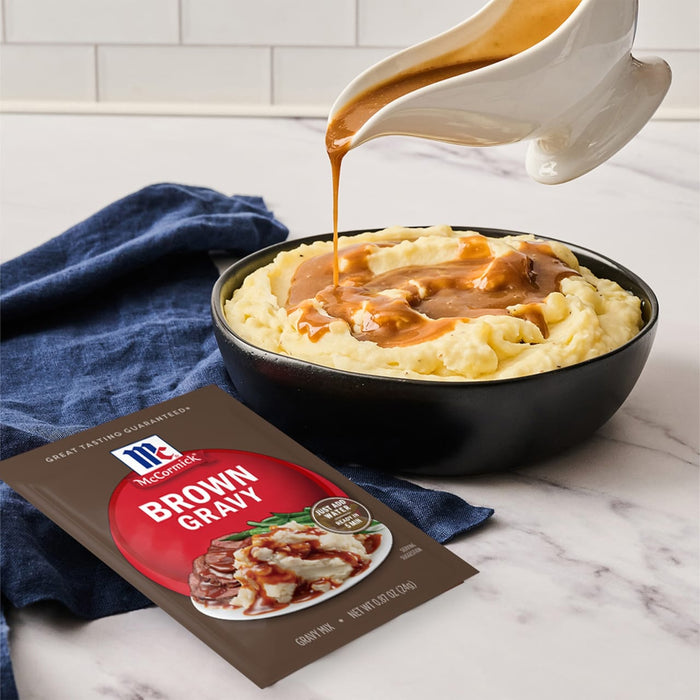 A bowl of mashed potatoes with McCormick Brown Gravy being poured over it.