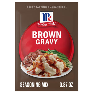 The packaging for Mccormick Brown Gravy Mix .87 Oz is displayed with a serving suggestion of the gravy poured over mashed potatoes, roast beef, and green beans.
