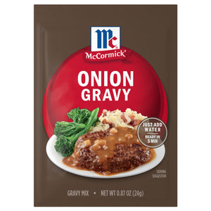 A brown packet of Mccormick Onion Gravy Mix .87 Oz is shown with a serving suggestion of the gravy over a meat patty with mashed potatoes and broccolini.