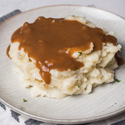 A plate of mashed potatoes topped with gravy.