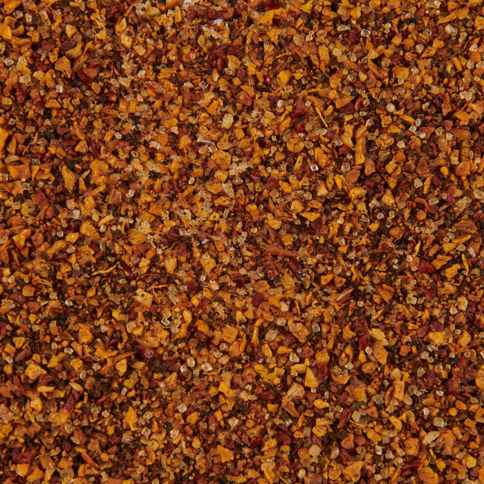 A detailed close-up displays Mccormick Grill Mates Hamburger Seasoning Granules 2.75 Oz, a vibrant blend of reddish-brown and orange spices mixed with clear salt crystals.