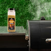 A bottle of Pit Boss Grilla Rub seasoning sits next to a smoker, suggesting its use in grilling.