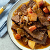 ['A plate of pot roast with potatoes, carrots, and onions.']