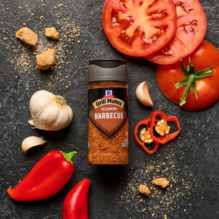 A bottle of McCormick Grill Mates Montreal Steak Seasoning is surrounded by fresh ingredients like tomatoes, garlic, and peppers.