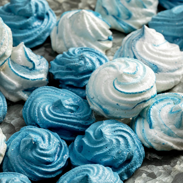 A close-up of numerous blue and white swirled meringue cookies, showcasing the vibrant effect of Mccormick Culinary Blue Food Coloring.