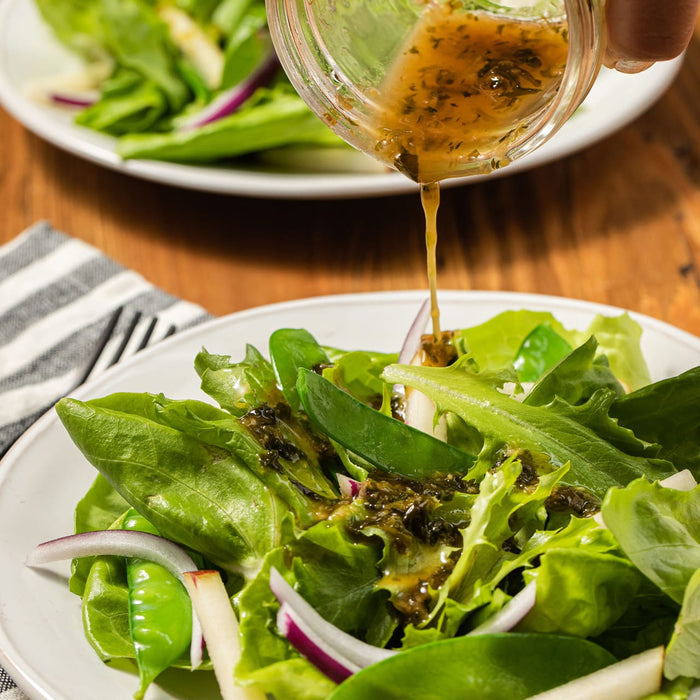 A fresh salad is being dressed with a flavorful vinaigrette, highlighting its appeal as a healthy and delicious meal option.