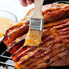 A glazed ham is being brushed with a sweet sauce, ready for serving.
