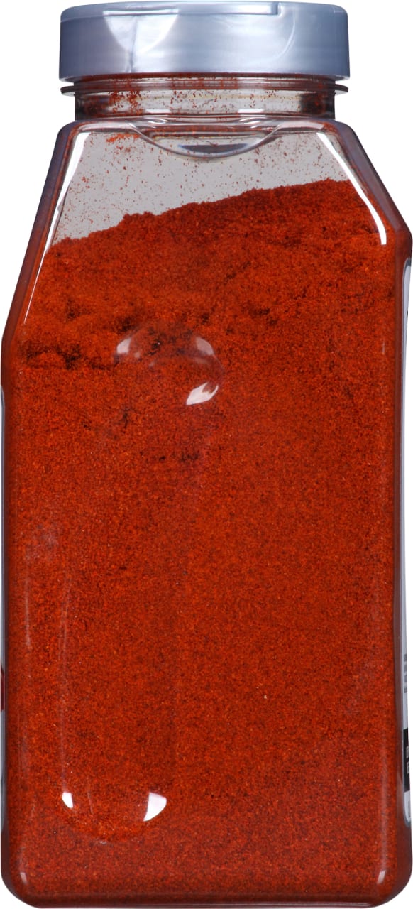 A clear plastic jar filled with red chili powder.