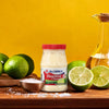 A jar of McCormick Mayonesa Mayonnaise with limes and salt on a wooden table.