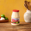 A jar of McCormick Mayonesa Mayonnaise with limes and garlic in the background.