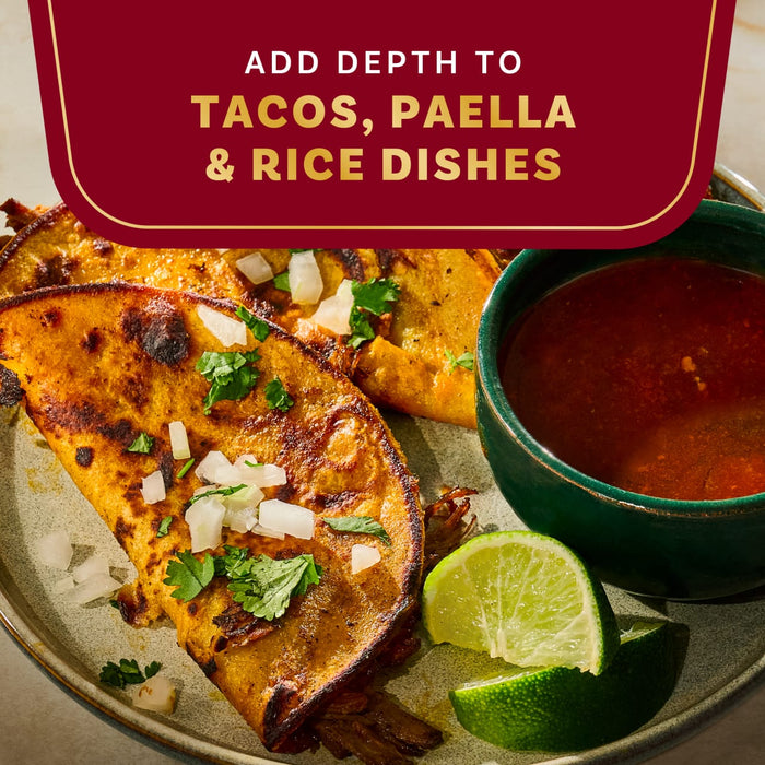 A close-up shot of tacos with a side of dipping sauce and lime wedges, highlighting the product's ability to add depth to tacos, paella, and rice dishes.