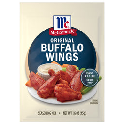 A packet of Mccormick Original Buffalo Wing Seasoning Mix 1.6 Oz featuring a plate of spicy glazed chicken wings served with celery sticks and dipping sauce.
