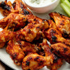 A plate of crispy golden-brown chicken wings with a side of celery and blue cheese dressing.