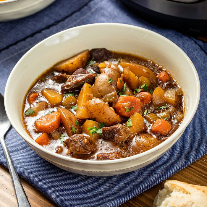 A hearty bowl of beef stew with potatoes and carrots, garnished with parsley.
