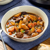 A hearty bowl of beef stew with potatoes and carrots, garnished with parsley.