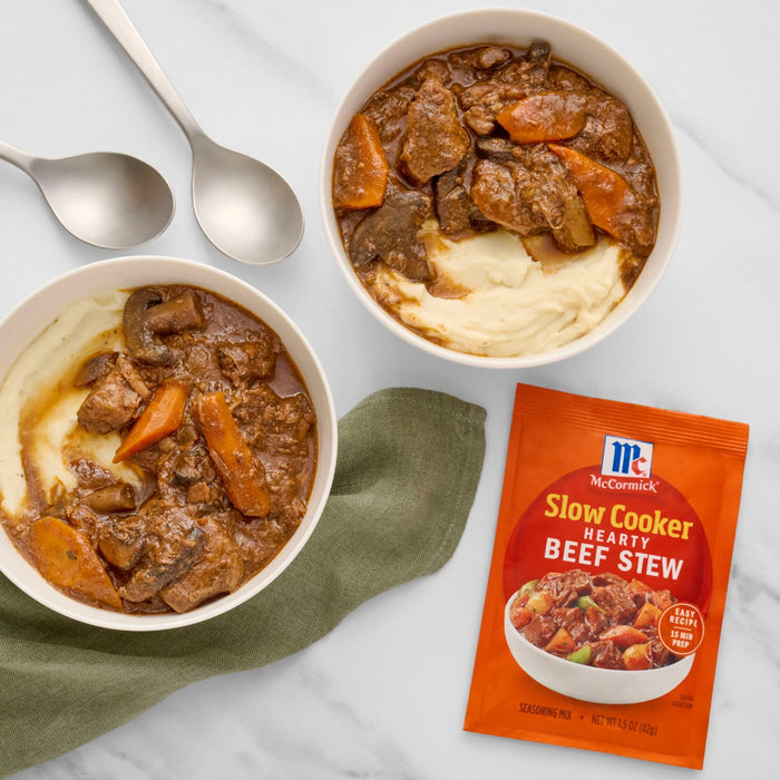 Two bowls of beef stew with mashed potatoes and a packet of McCormick Slow Cooker Beef Stew seasoning.