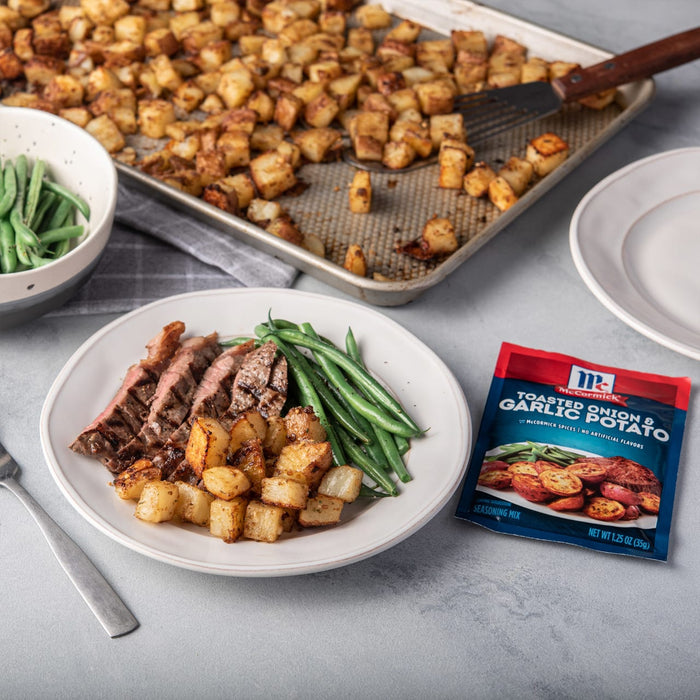 A plate of steak green beans and roasted potatoes with a McCormick Toasted Onion &amp; Garlic Potato seasoning packet.