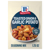 A packet of Mccormick Toasted Onion And Garlic Seasoning Mix 1.25 Oz is displayed in front of a white bowl filled with seasoned and roasted potatoes.