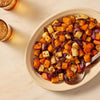 A platter of roasted root vegetables, seasoned to perfection with Mccormick Toasted Onion And Garlic Seasoning Mix 1.25 Oz, is served on a marble countertop next to two iced drinks.