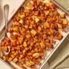 A baking sheet holds roasted sweet potatoes and apples, seasoned to perfection with Mccormick Toasted Onion And Garlic Seasoning Mix 1.25 Oz, with a serving spoon ready to dish them out.