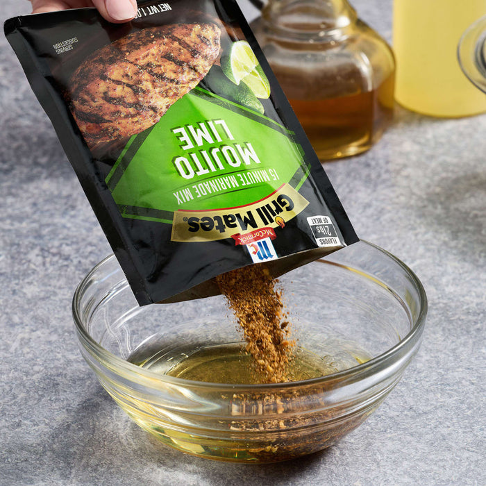 A hand pours McCormick Grill Mates Mojito Lime seasoning into a bowl with oil.