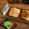 Two pieces of fish are being marinated with McCormick Roasted Lime seasoning in a glass baking dish.