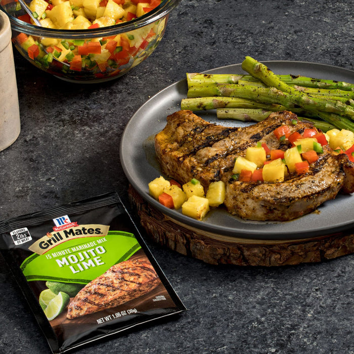 A grilled pork chop seasoned with Grill Mates Mojito Lime seasoning is served with grilled asparagus and a pineapple salsa.