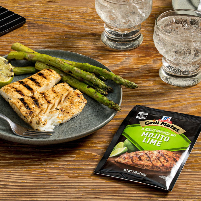 A plate of grilled fish and asparagus with a McCormick Mojito Lime seasoning packet next to it.
