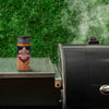 A bottle of Grill Mates Smokehouse Maple seasoning sits on a grill.