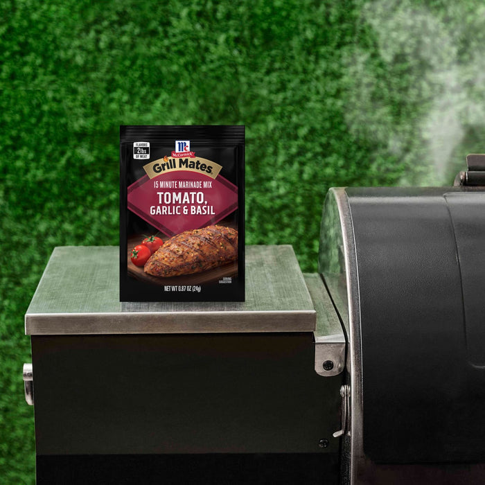 A McCormick Grill Mates Tomato &amp; Garlic Marinade package sits on a grill, suggesting a grilling or cooking theme.