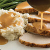 A plate of mashed potatoes turkey and gravy.