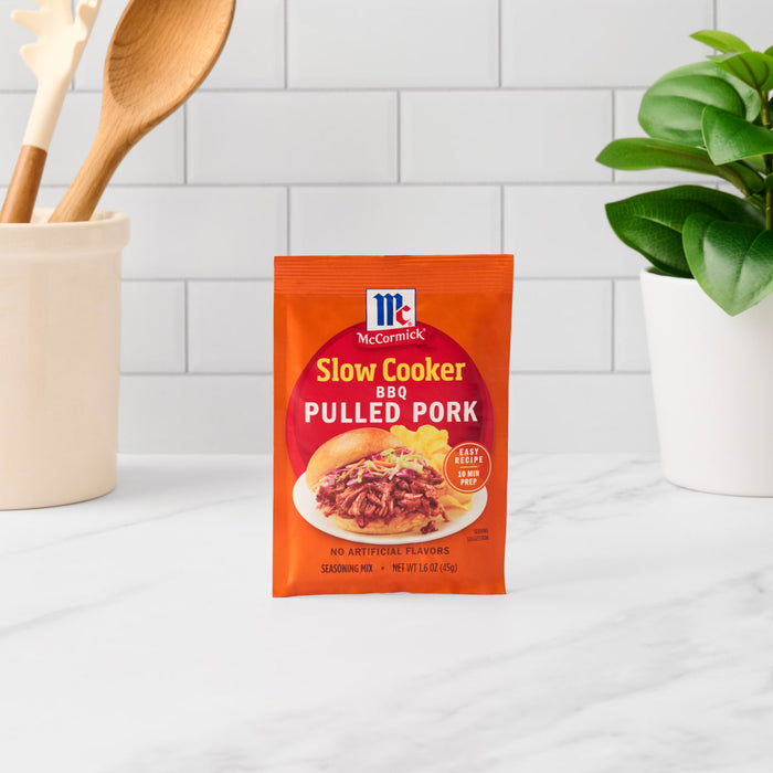 A packet of McCormick Slow Cooker BBQ Pulled Pork seasoning mix sits on a counter.