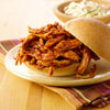 A pulled chicken sandwich with barbecue sauce is served with a side of coleslaw.