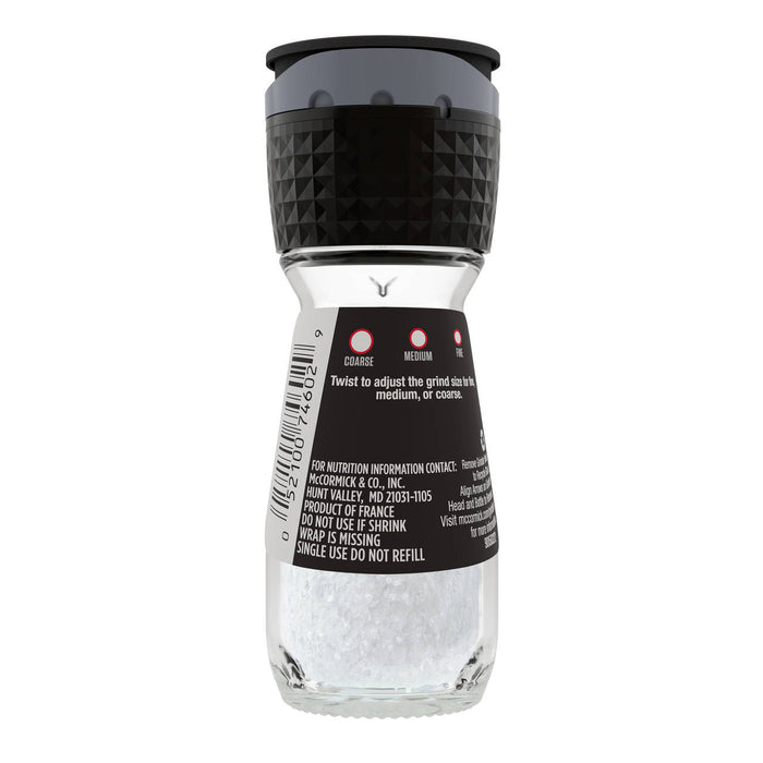 A clear glass grinder bottle of Mccormick Salt Sea 2.12 Oz, featuring a black and gray top with adjustable grind settings for coarse, medium, or fine, and a label displaying McCormick &amp; Co. Inc. contact information and a barcode.