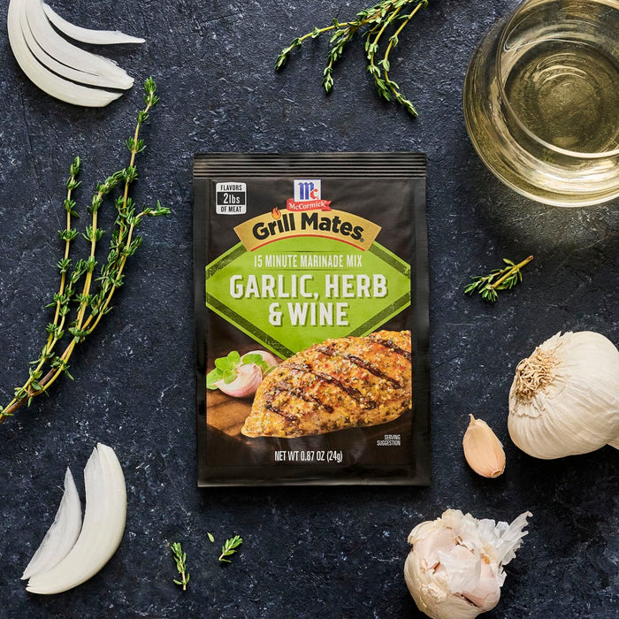 McCormick Grill Mates Garlic Herb &amp; Wine marinade mix is displayed with fresh thyme, garlic, onion, and oil, suggesting a flavorful grilling experience.
