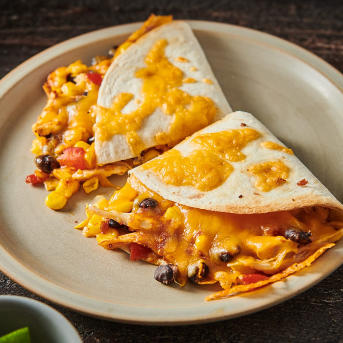 Two quesadillas filled with chicken corn black beans and cheese on a plate.