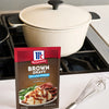 A packet of McCormick Brown Gravy mix sits next to a pot and whisk on a stovetop.