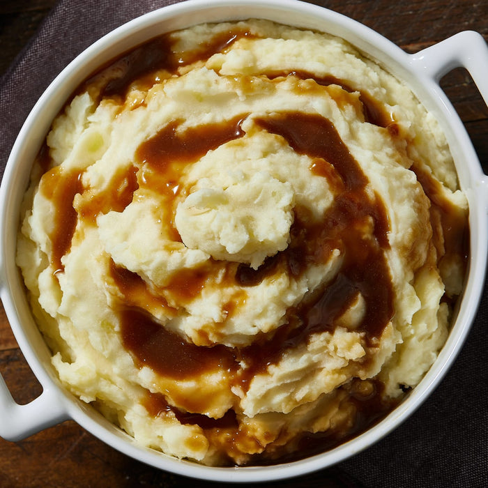 A bowl of creamy mashed potatoes topped with savory brown gravy.