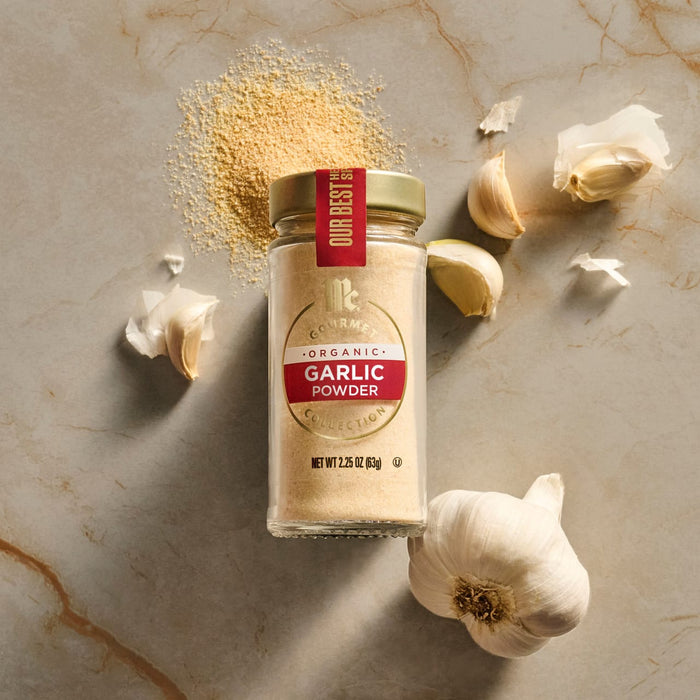 A jar of Regal Ground Garlic Powder is displayed with loose powder and garlic cloves on a marble surface.