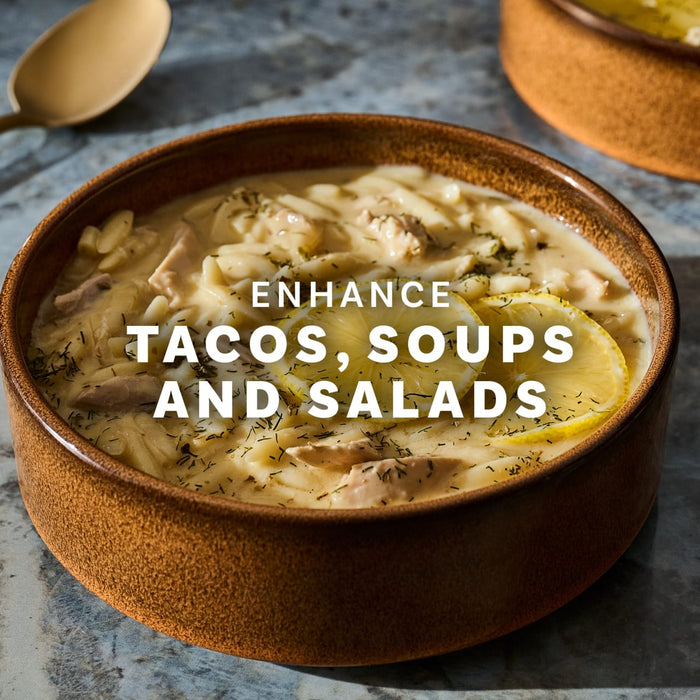 A bowl of creamy soup with pasta and lemon slices, suggesting it can enhance tacos, soups, and salads.