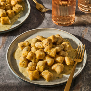 A plate of gnocchi with sauce and a fork, showcasing a delicious meal.