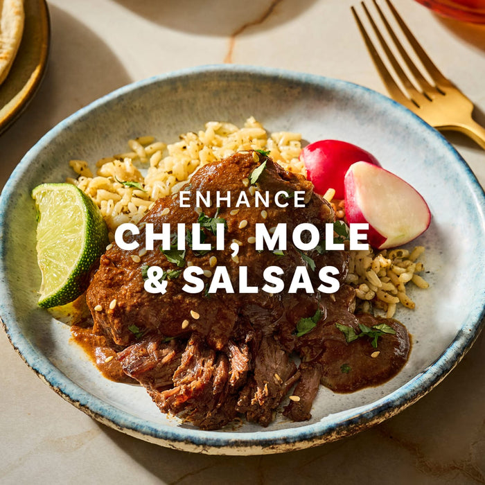 A plate of chili mole and salsa with rice, radishes, and a lime wedge.