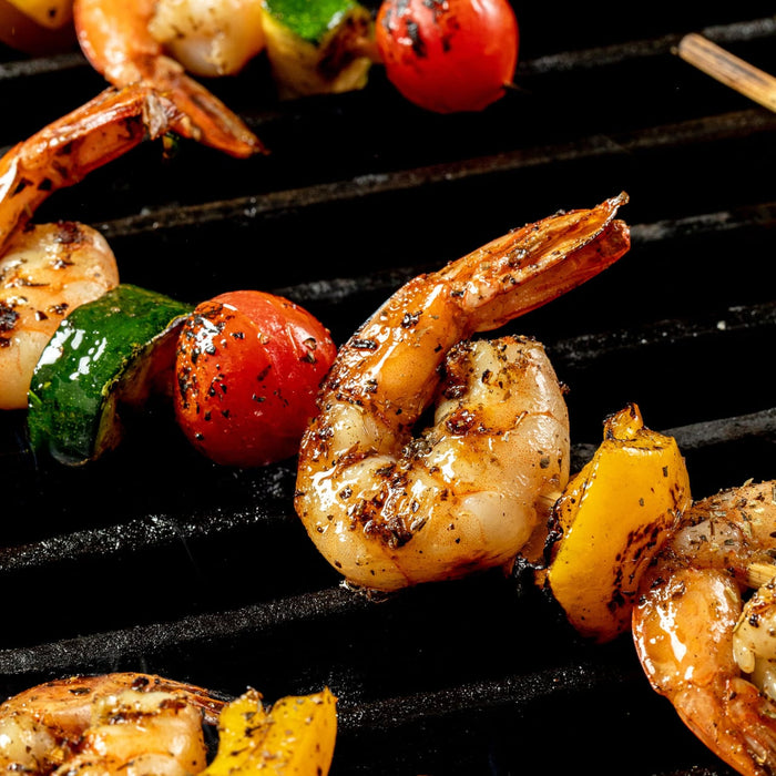 Grilled shrimp skewers with vegetables on a barbecue grill.