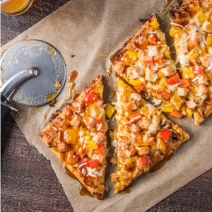 A freshly cut pizza with colorful toppings sits on parchment paper next to a pizza cutter, showcasing a delicious and inviting meal.