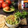 A bowl of guacamole with tortilla chips and McCormick Mexican Taco Truck seasoning being sprinkled on top.