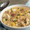 A bowl of creamy chicken and corn chowder with potatoes and bacon.