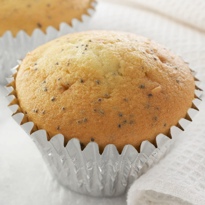 A close-up of a poppy seed muffin in a silver cupcake liner.